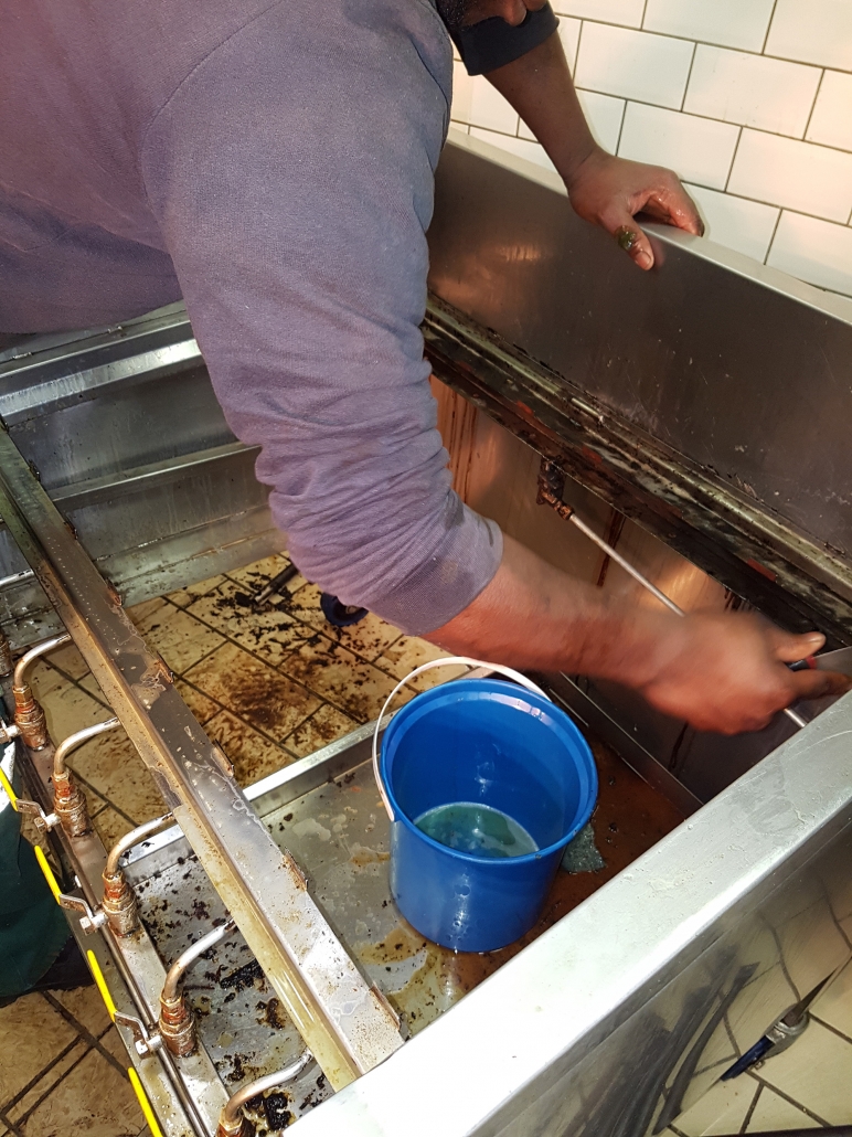 Technician deep cleaning inside a stripped-down kitchen unit