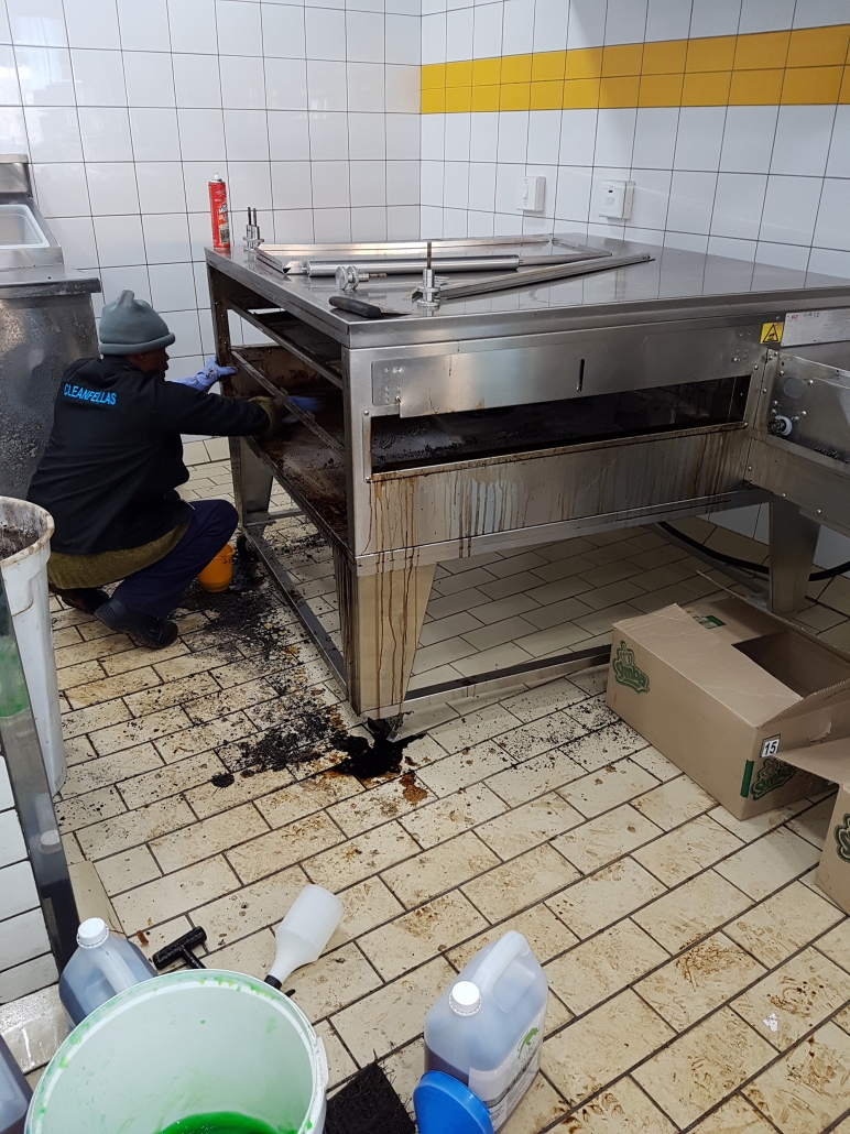 Cleanfellas technician degreasing a stainless steel grill unit on site